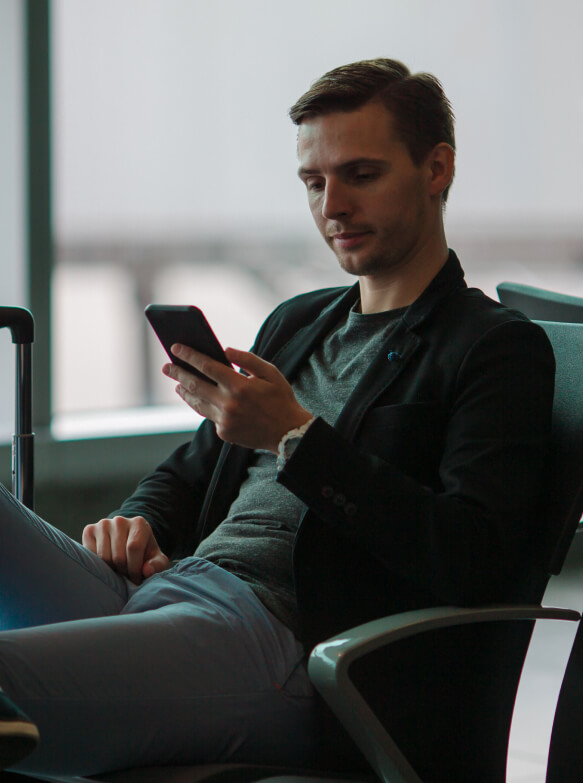 man on his phone sitting in airport terminal