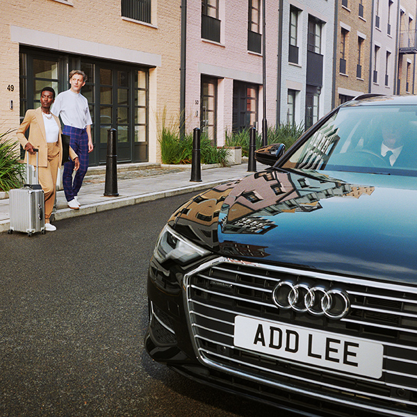 Addison Lee executive car with man and woman getting in with suitcase
