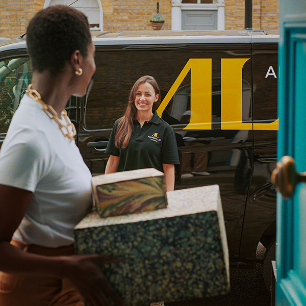 Addison Lee Courier driver delivering parcels to a woman standing at the door of her house